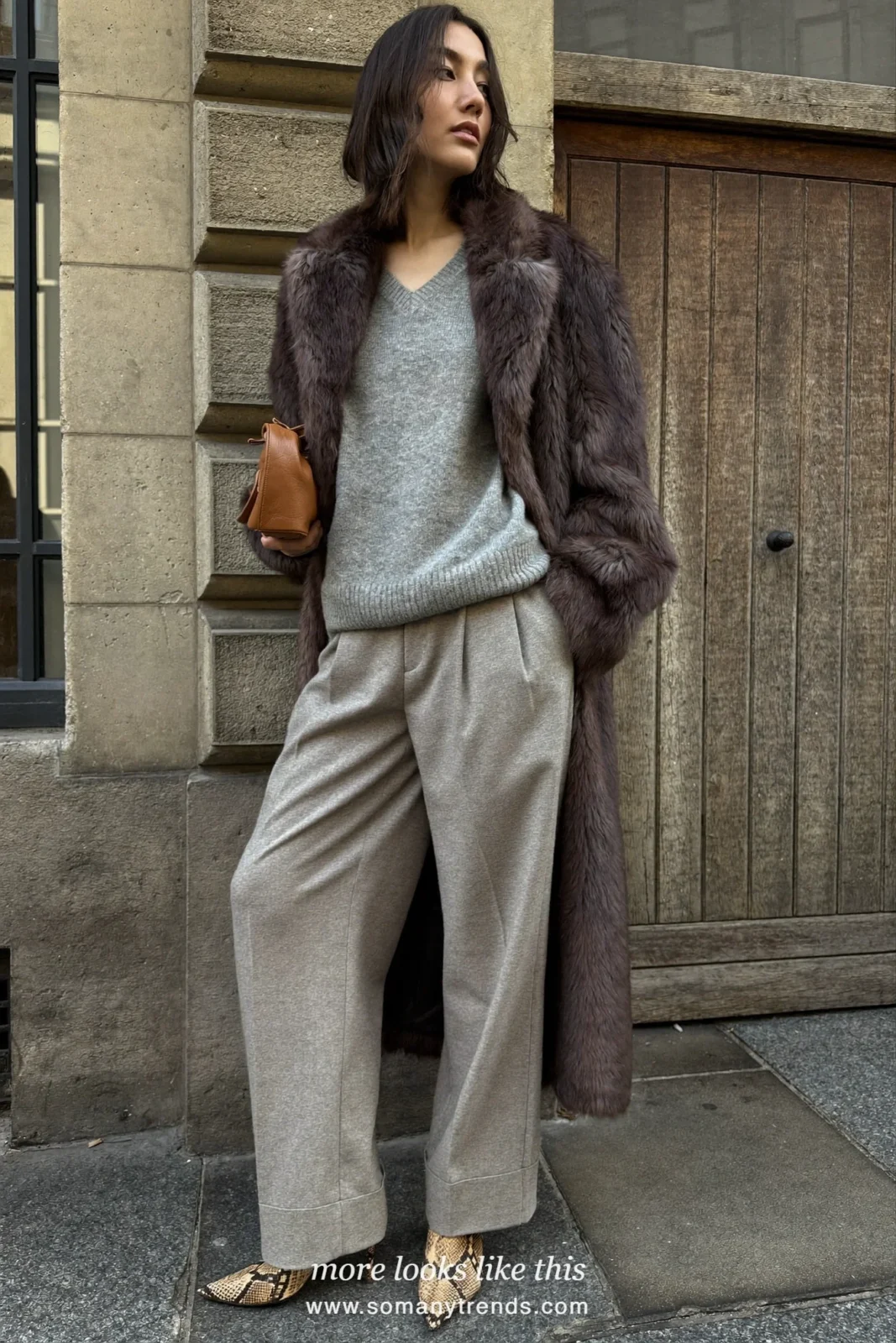 Long chocolate faux fur coat over a gray V-neck sweater, gray pleated pants and snakeskin ankle boots, outfit 2