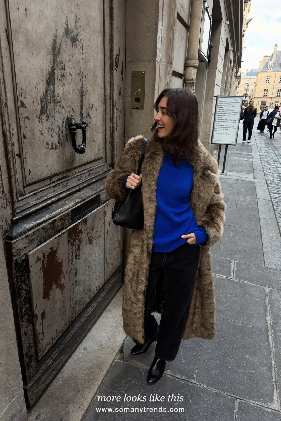 Long brown faux fur coat over a cobalt blue sweater, black wide pants and black ankle boots, outfit 23