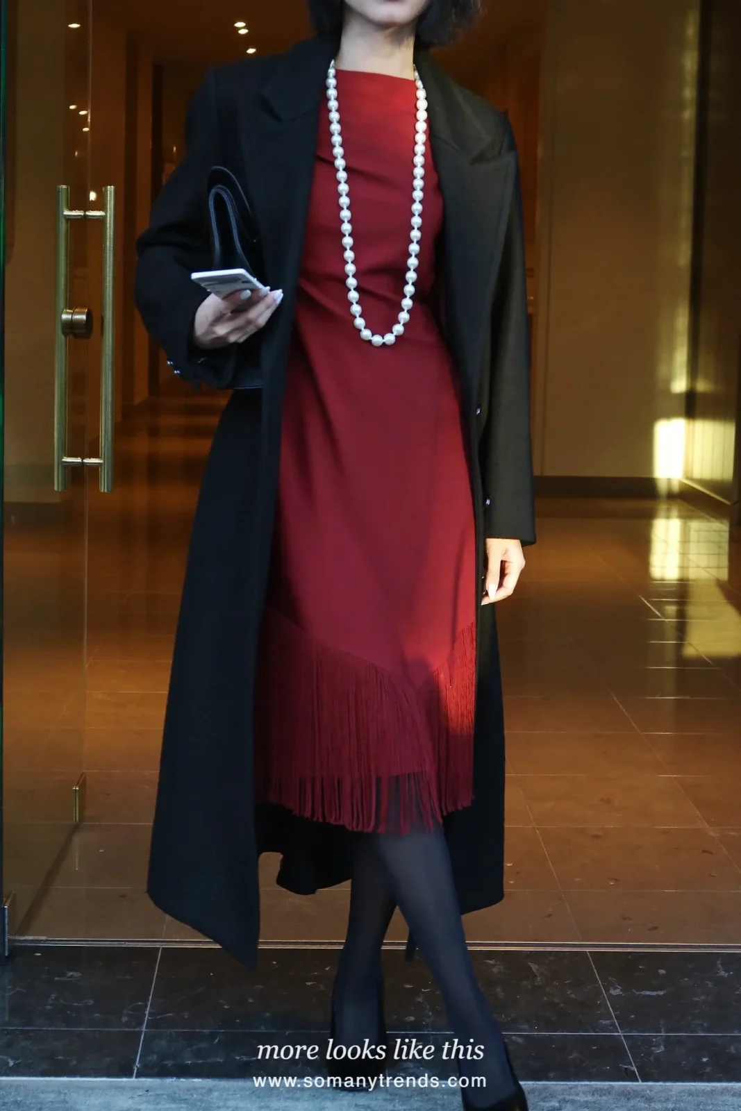 Woman in burgundy drop-waist fringe midi dress, long pearl strand, black opaque tights and black pumps, look 2