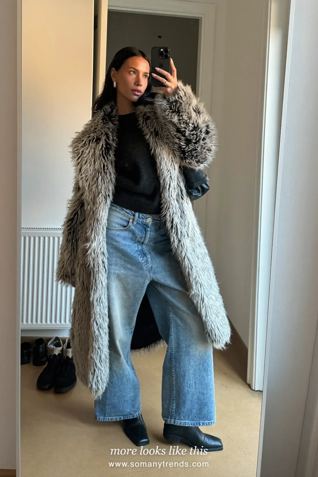 Woman in gray shaggy faux fur long coat, black knit, wide straight blue jeans and black ankle boots, look 8