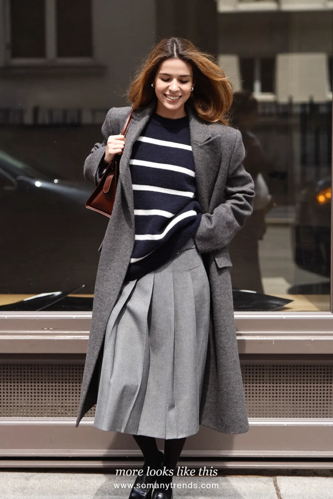 Woman in navy and white striped knit sweater, gray pleated midi skirt, gray coat, black tights and loafers, look 10