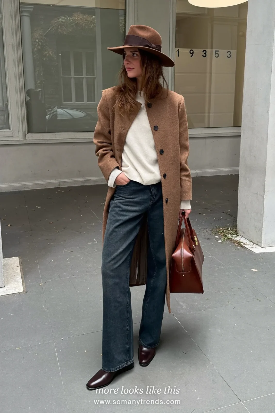Woman in brown wool felt wide-brim hat, camel long coat, cream knit, dark wide jeans and brown boots, look 11