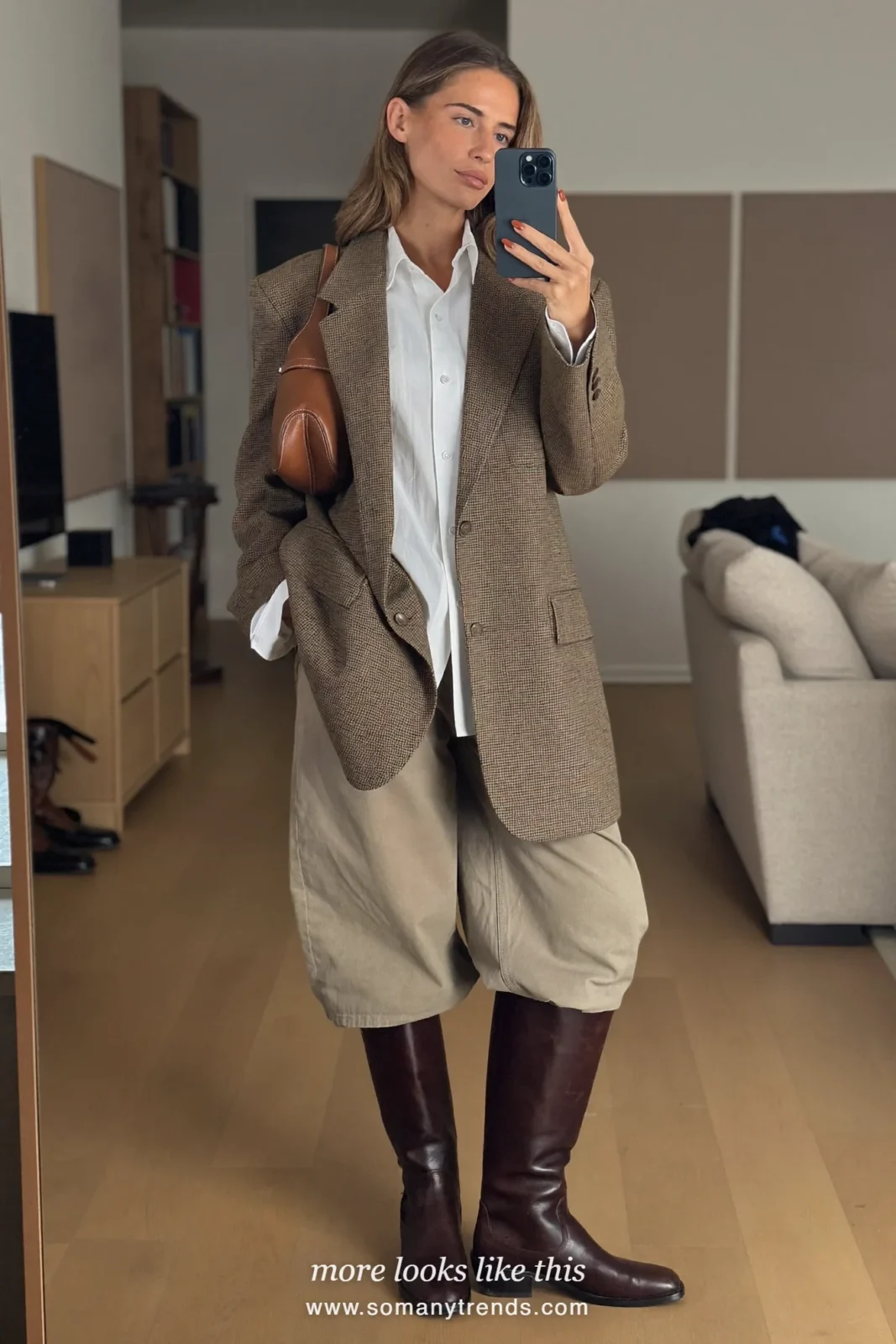 Woman in brown tweed jacket, white shirt, beige jodhpur-style pants and tall brown riding boots, look 12