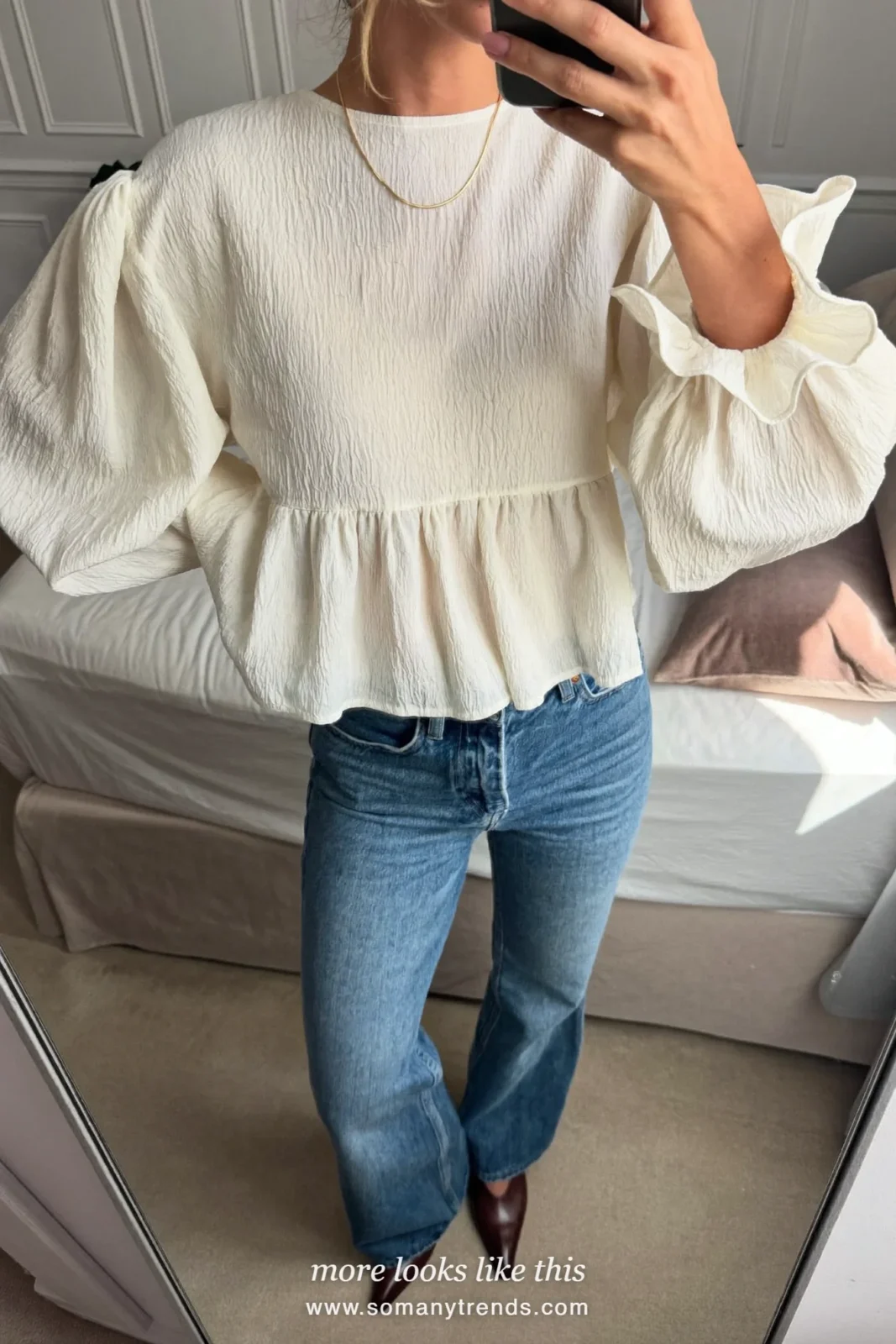 Woman in caramel suede shearling-collar jacket, cream ruffled blouse, flared blue jeans and brown boots, look 16