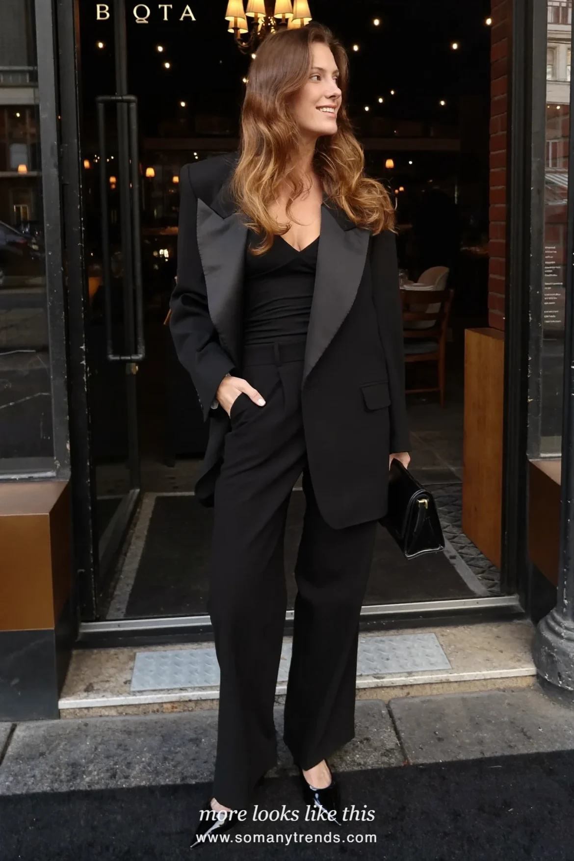 Woman in black long tailored blazer, black V-neck top, black straight pants and black pointed pumps, look 21