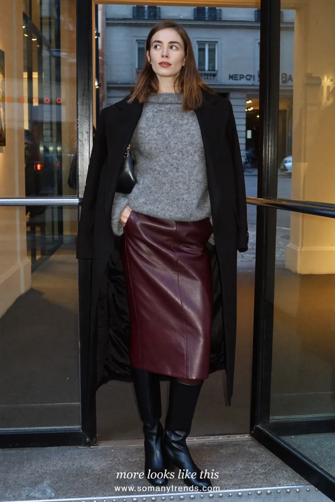 Woman in burgundy leather midi skirt, gray oversized knit, black tights and black tall boots, look 23