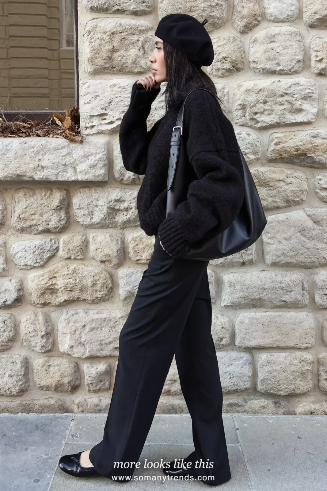 Woman in a black wool beret, black sweater, wide-leg black pants and black flats on a stone street, outfit 2