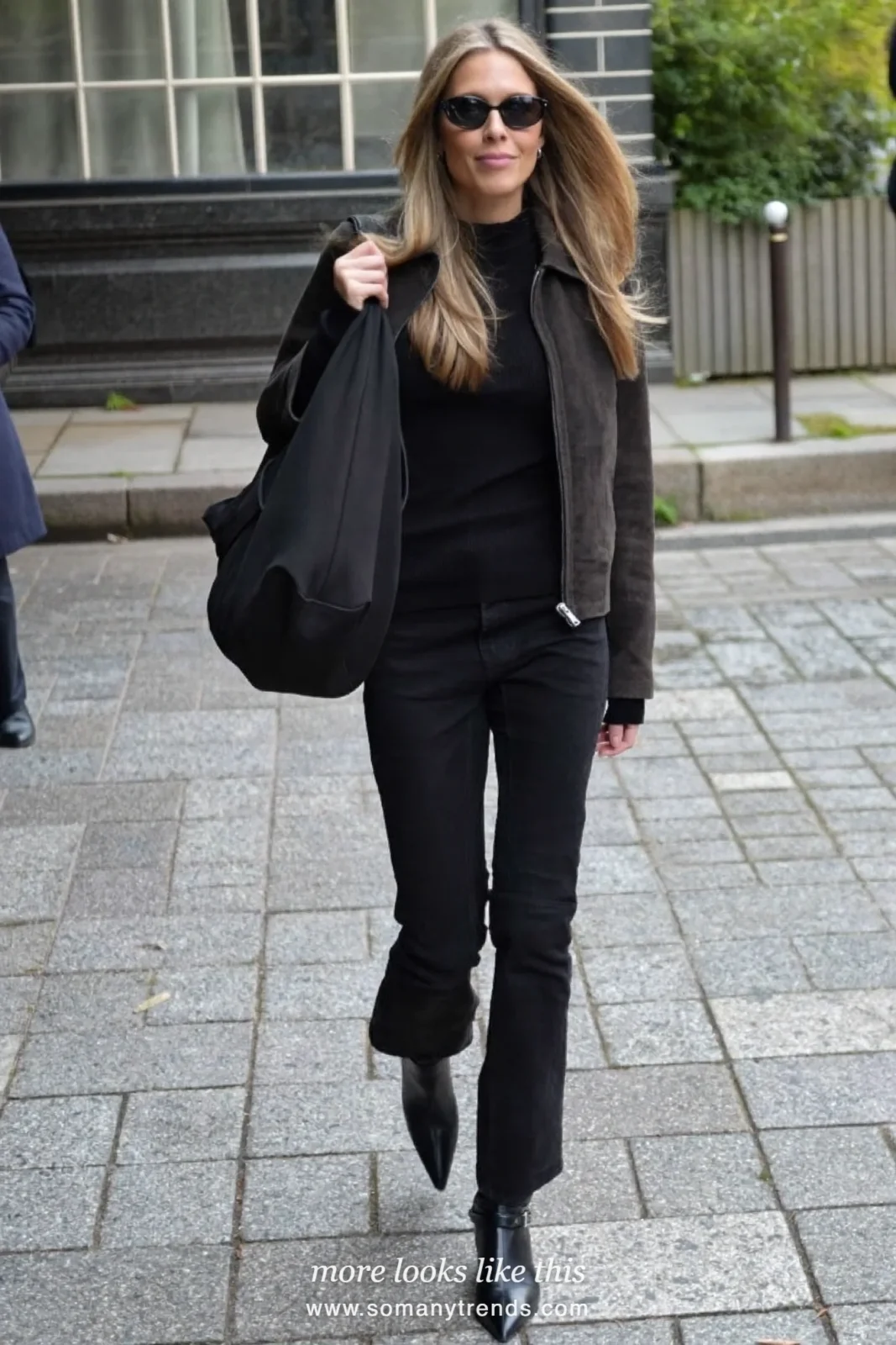 Woman in a black suede jacket, black knit top, black bootcut pants and black boots on a city street, outfit 6