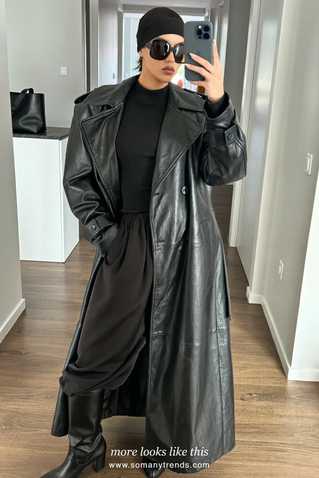 Woman in a black leather trench, black head wrap, black pants and black boots on a stone sidewalk, outfit 12