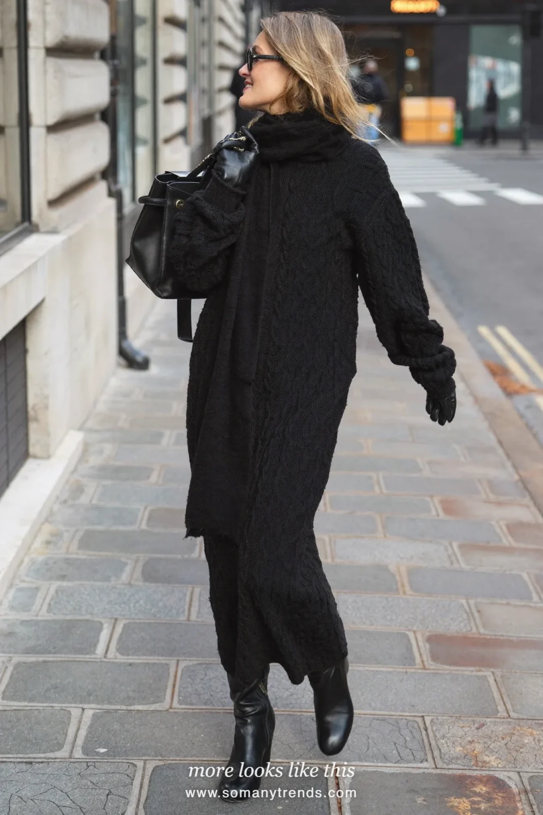 Woman in a black knit maxi dress, tall black boots and long black scarf on a city street, outfit 13