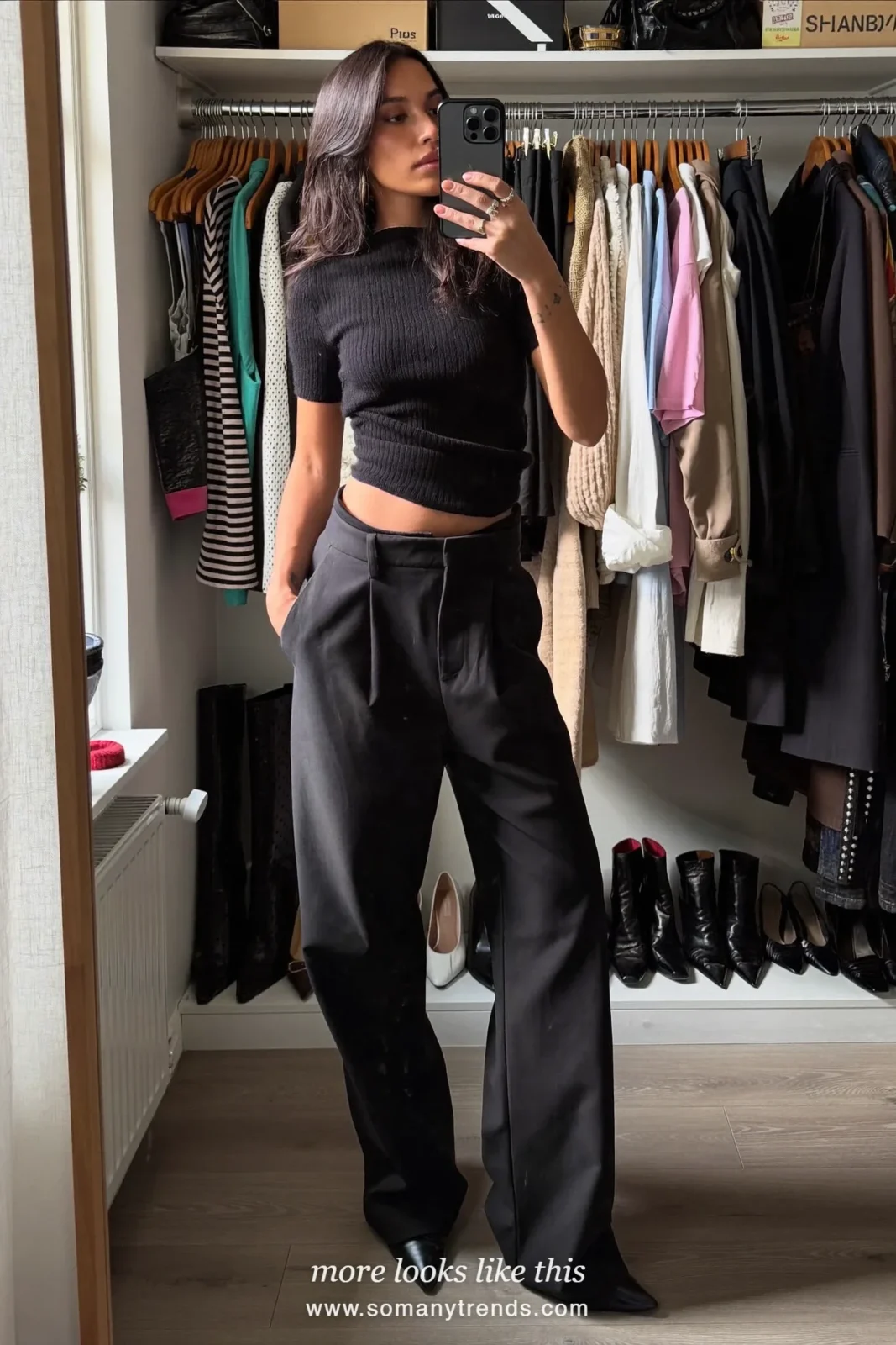 Woman in a black mock neck knit and wide black pants on a stone street, mirror selfie at home, outfit 20