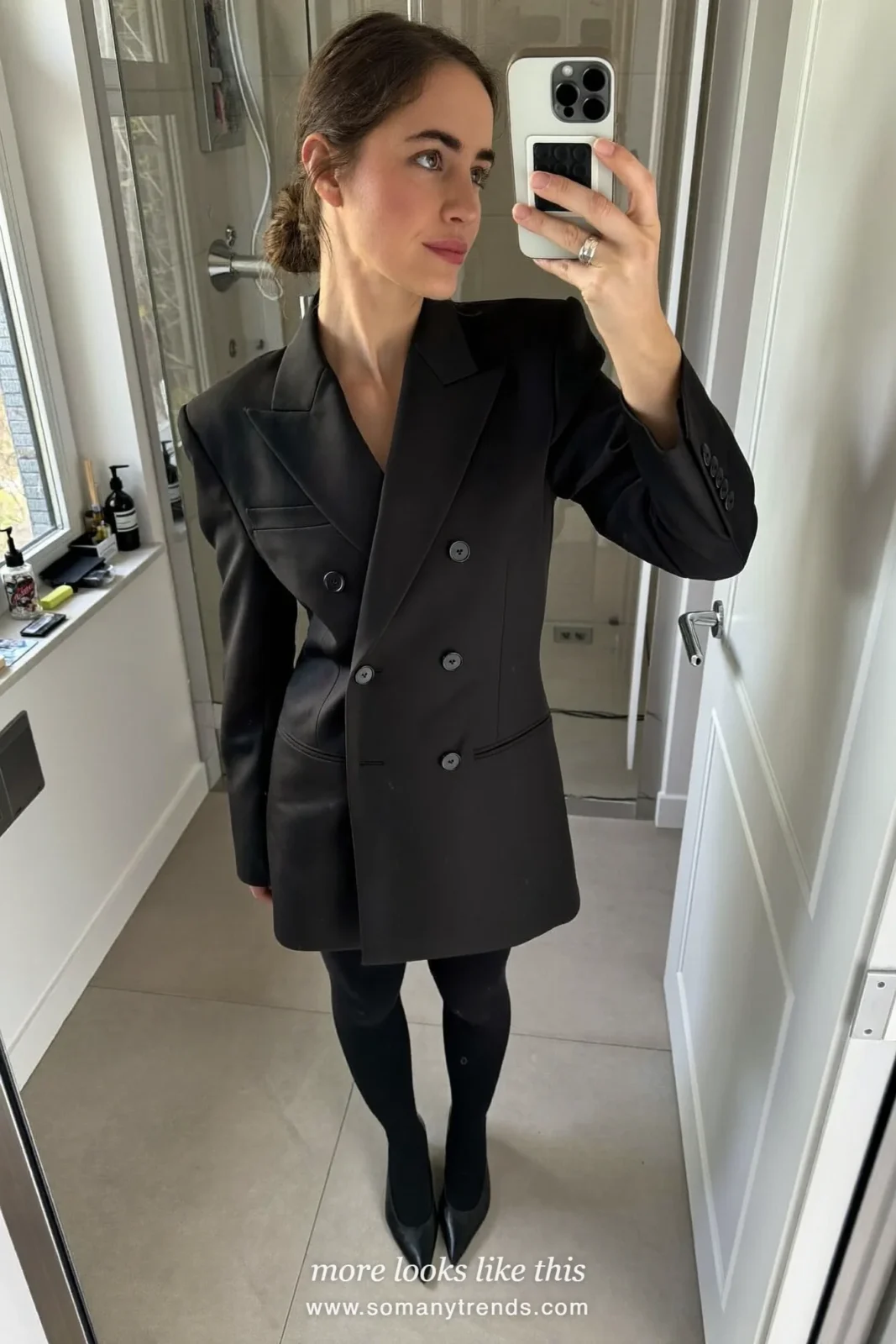 Woman in a black double-breasted blazer dress, black tights, pumps and leather gloves on a city street, outfit 24