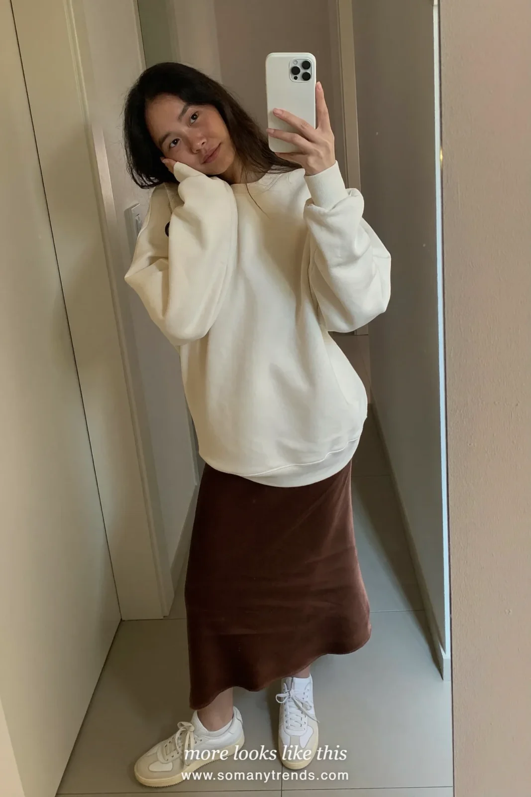 Woman in a mocha satin midi skirt, cream sweatshirt and white sneakers, house party outfit 16