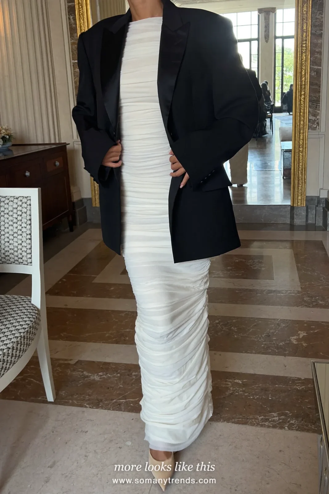 Woman in an ivory ruched column gown with a black tuxedo jacket over the shoulders, outfit 6