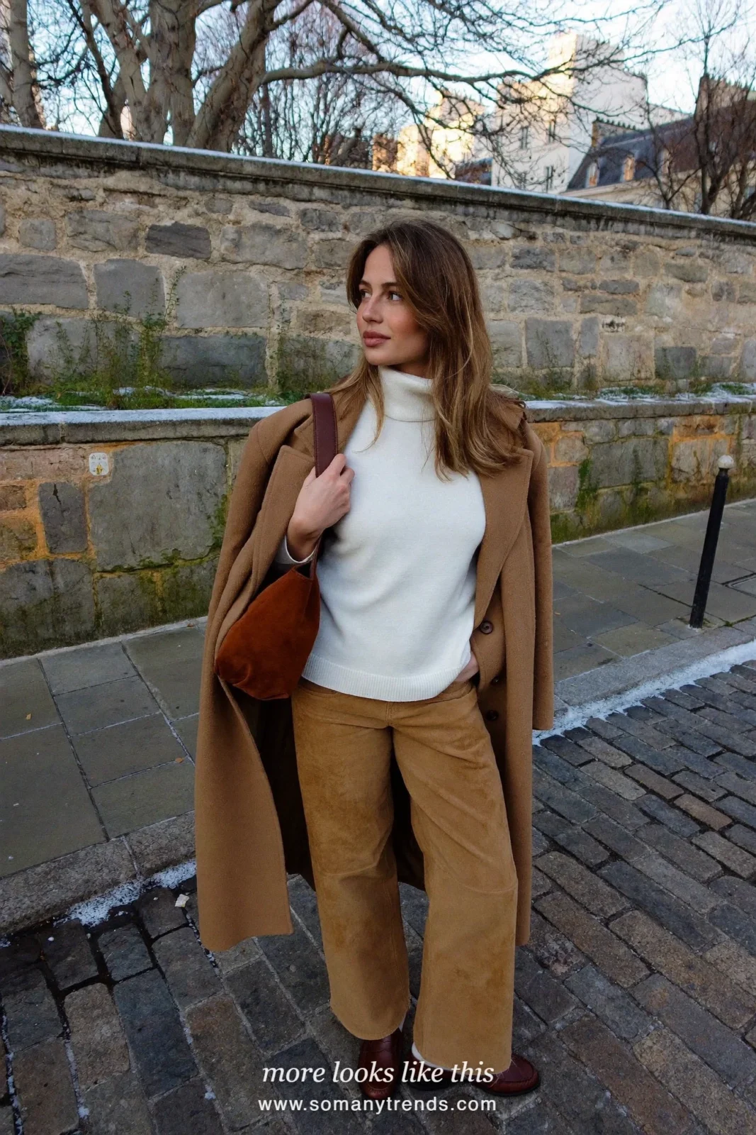 Woman in tan suede wide-leg pants, white turtleneck, camel coat and brown loafers with a brown leather bag, outfit 1