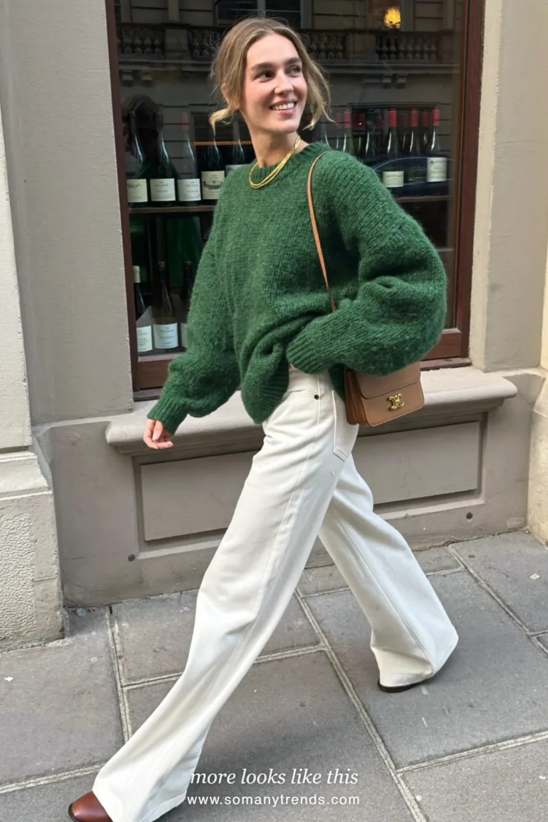 Woman in winter white wide-leg pants, forest green chunky knit, brown boots and tan bag, outfit 18