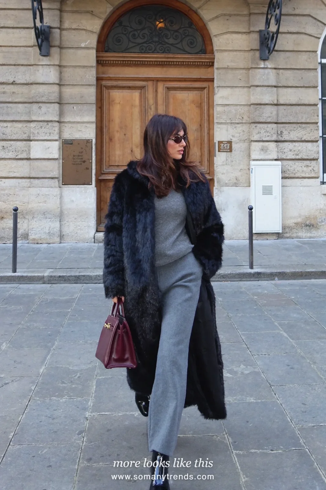 Long black faux fur coat over a gray sweater, gray pants, black boots and a burgundy top-handle bag, outfit 26