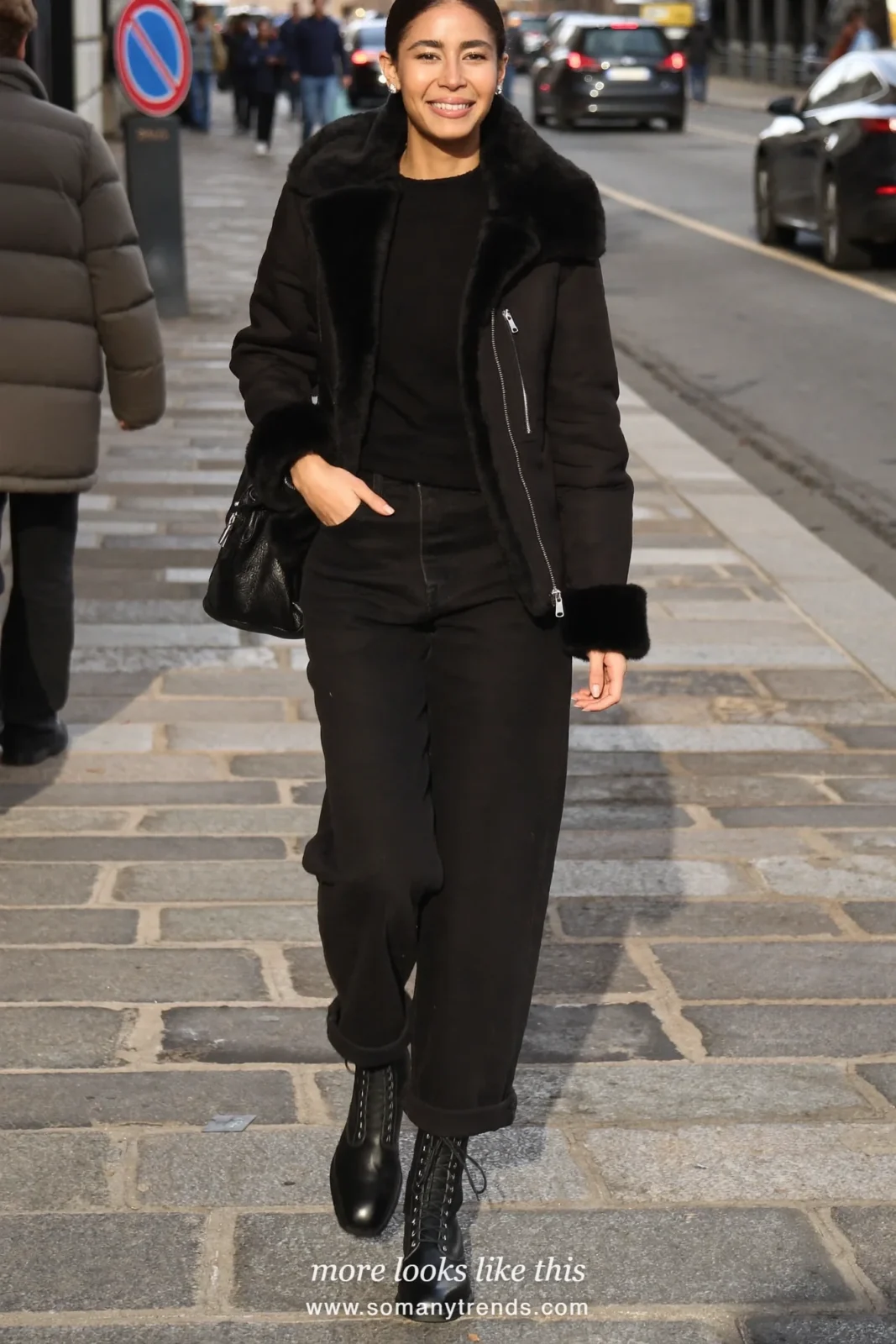 Woman in a black shearling collar jacket, black straight jeans and black boots on a city street, outfit 15