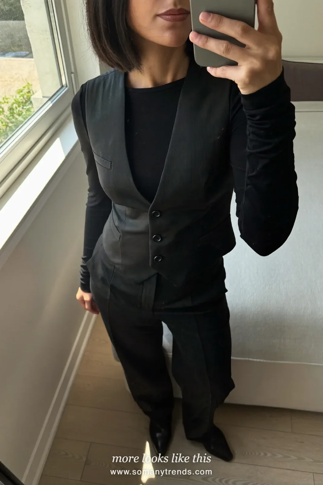 Woman in a black tailored vest, black long-sleeve top, wide-leg black pants and black boots, outfit 16