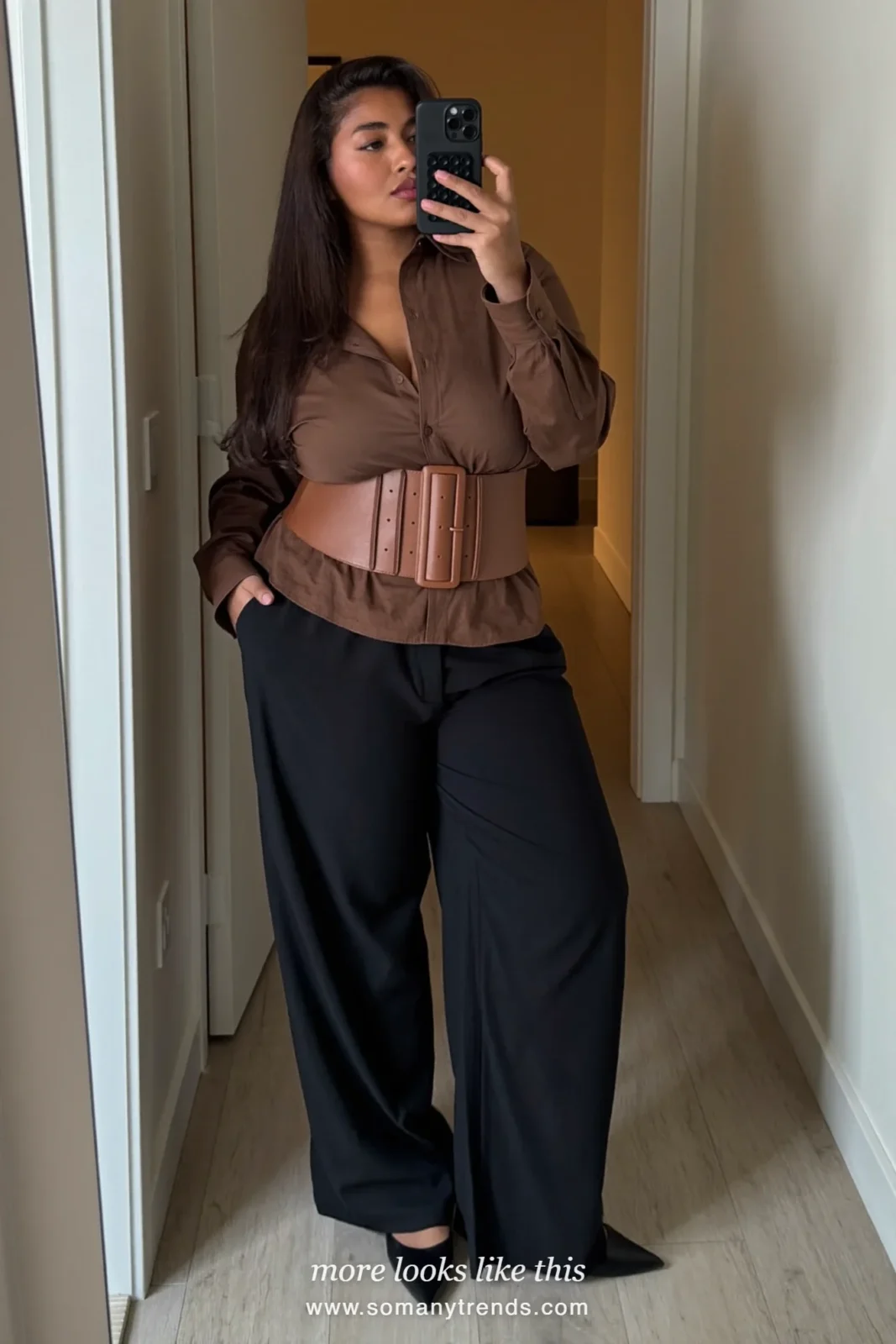 Woman in a brown shirt with a wide tan cummerbund belt, black wide pants and black flats on a Paris street, outfit 8
