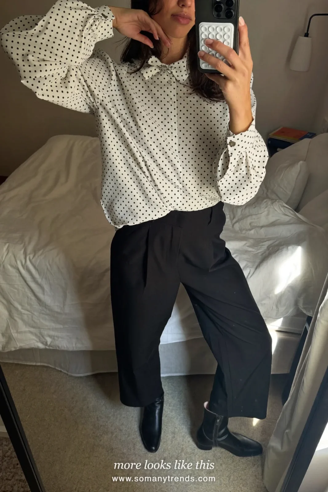 Woman in a white polka dot blouse, black wide pants and short black wool jacket with flat boots in Paris, outfit 12
