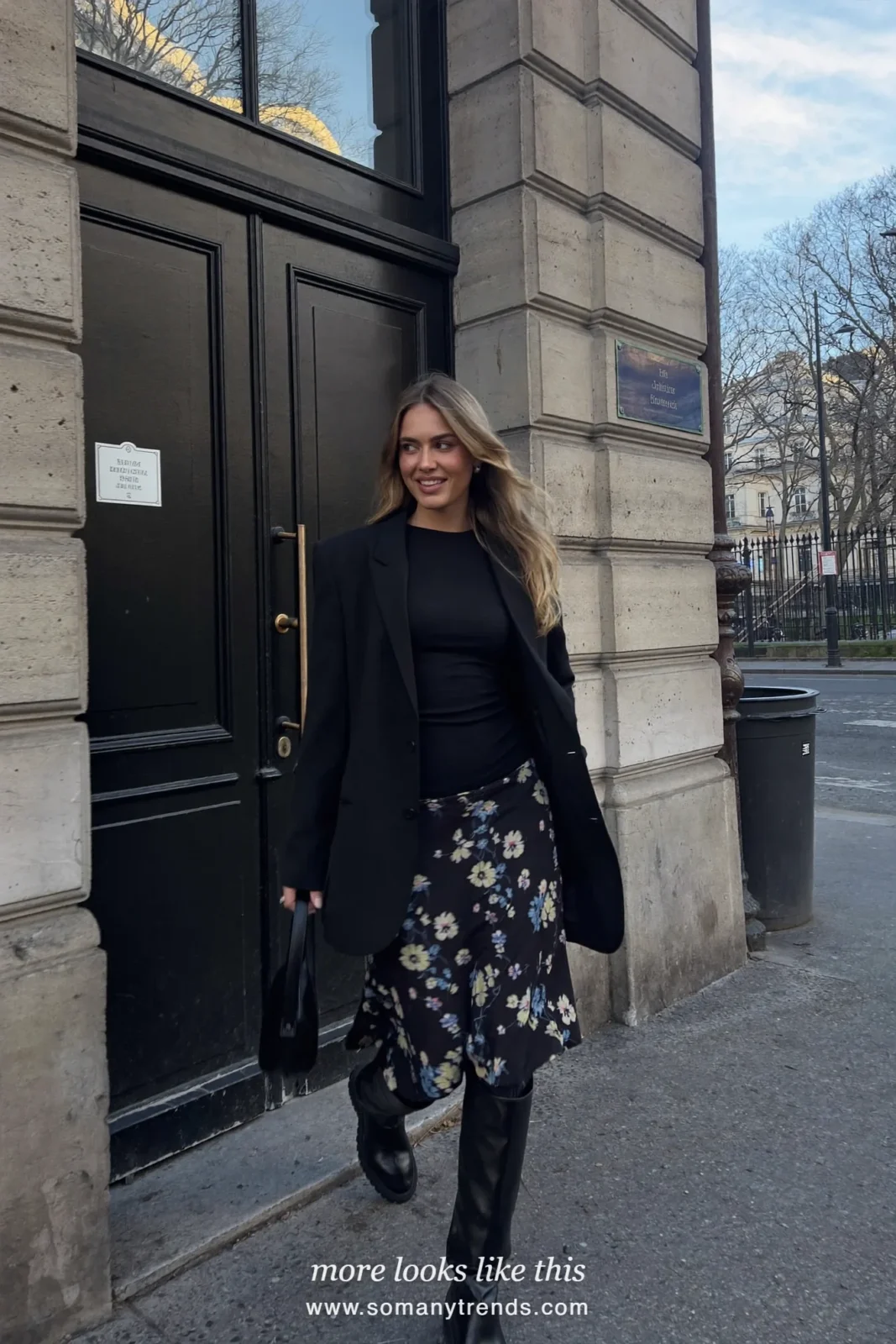 Woman in a long black blazer, dark floral midi skirt and black knee-high boots on a Paris street, outfit 17