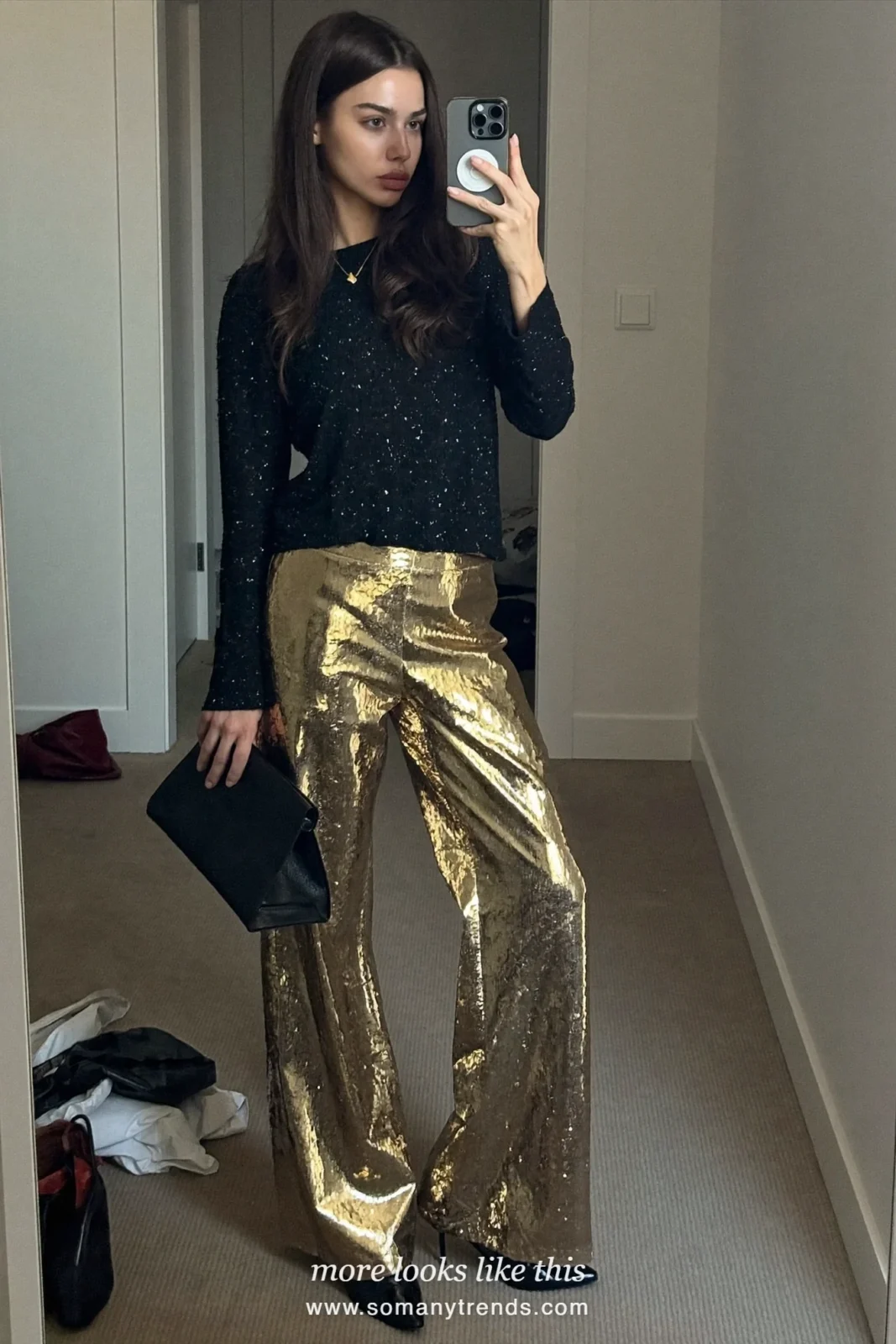 Woman taking a mirror selfie in a hallway wearing gold sequin wide-leg pants, a black knit top and black heeled boots, outfit 4