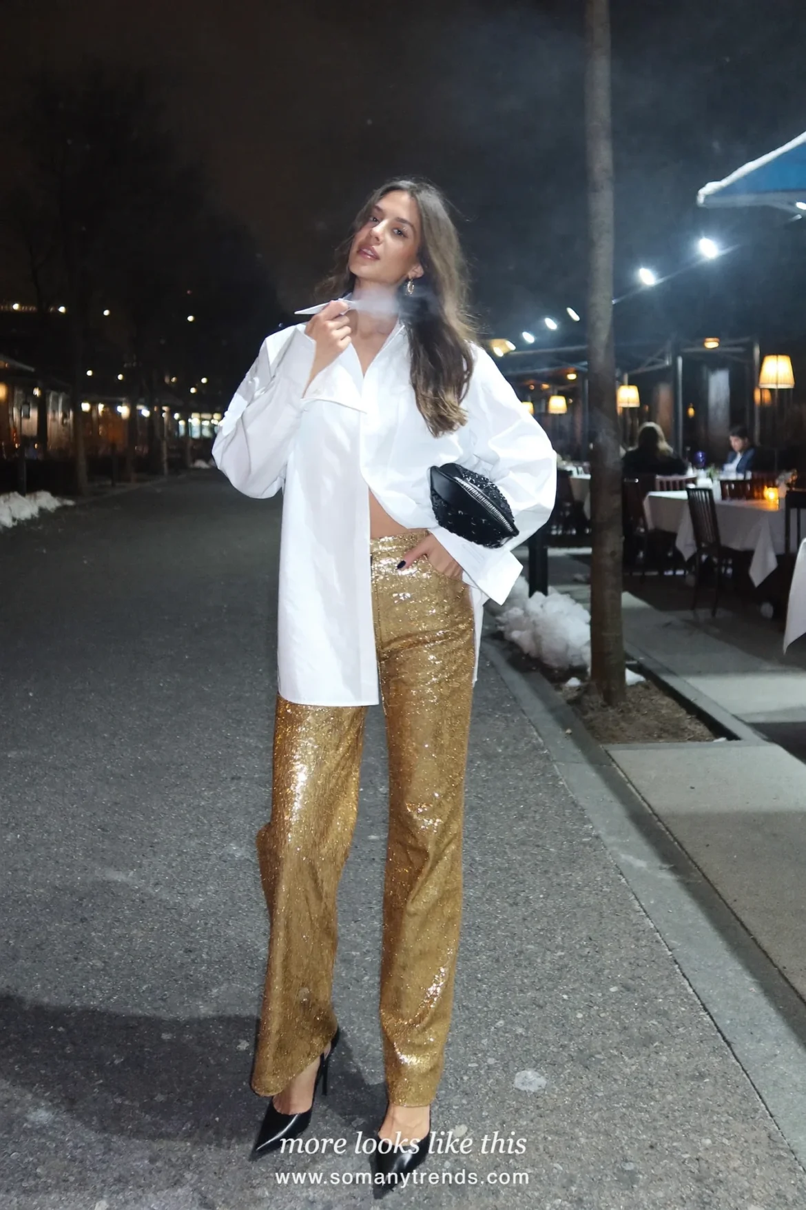 Woman in a white poplin shirt, gold sequin wide-leg pants and black pointed pumps outside a restaurant at night, outfit 15