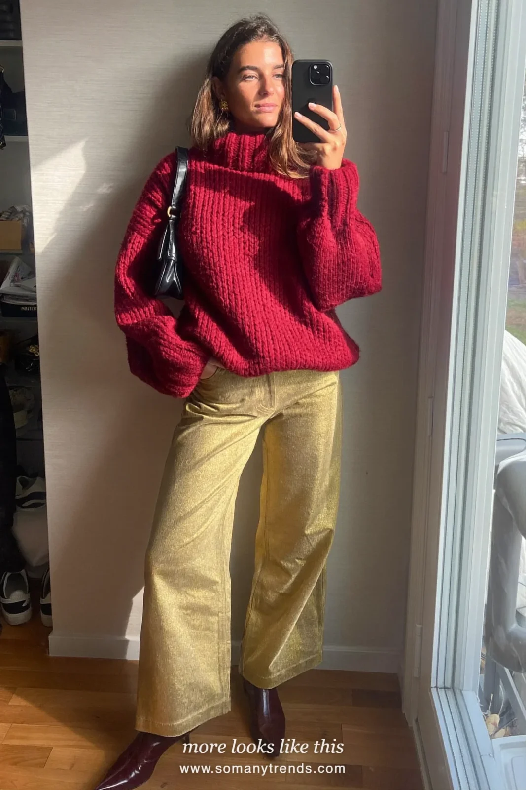 Woman in a burgundy knit sweater, gold metallic wide-leg pants and burgundy ankle boots on a city street at dusk, outfit 16