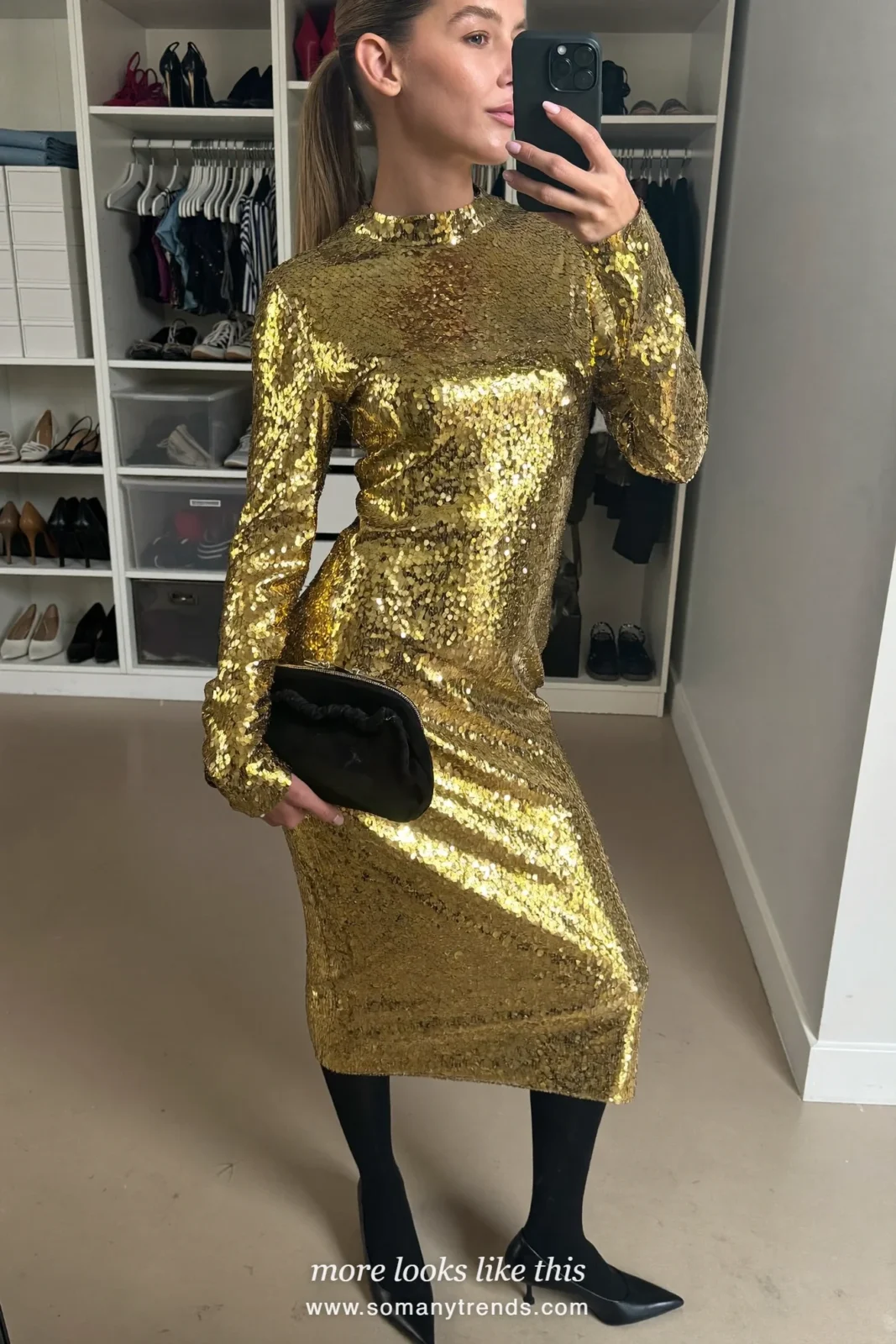 Woman taking a mirror selfie in a closet wearing a gold sequin midi dress with sleeves and black pumps, outfit 24