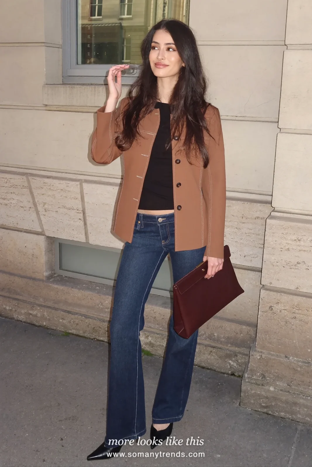 Woman in a camel blazer, black tee, dark indigo flare jeans and pointed loafers outdoors, outfit 11