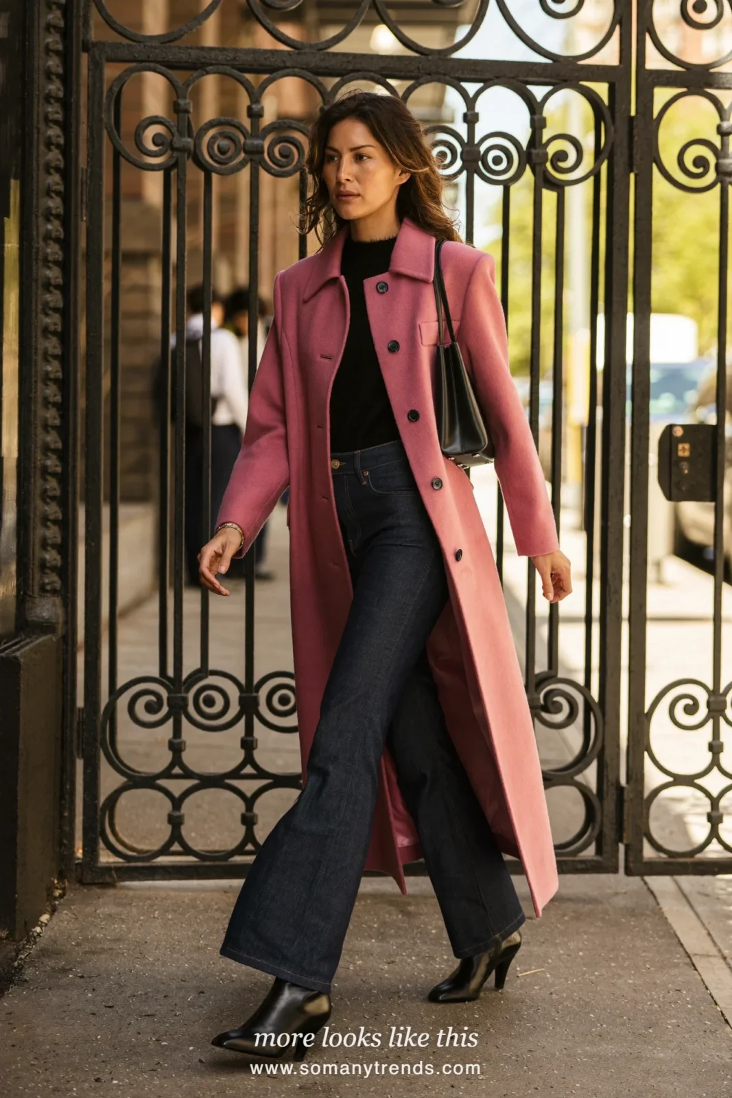 Woman in a rose wool coat, black knit top, dark blue flare jeans and black heeled boots on a city street, outfit 15