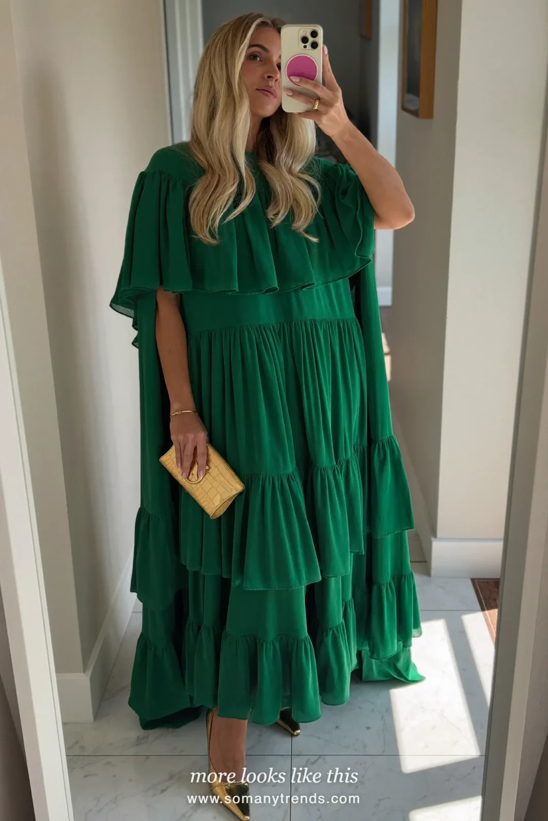 Woman in an emerald tiered ruffle gown with cape sleeves and gold sandals in a hotel ballroom, outfit 4