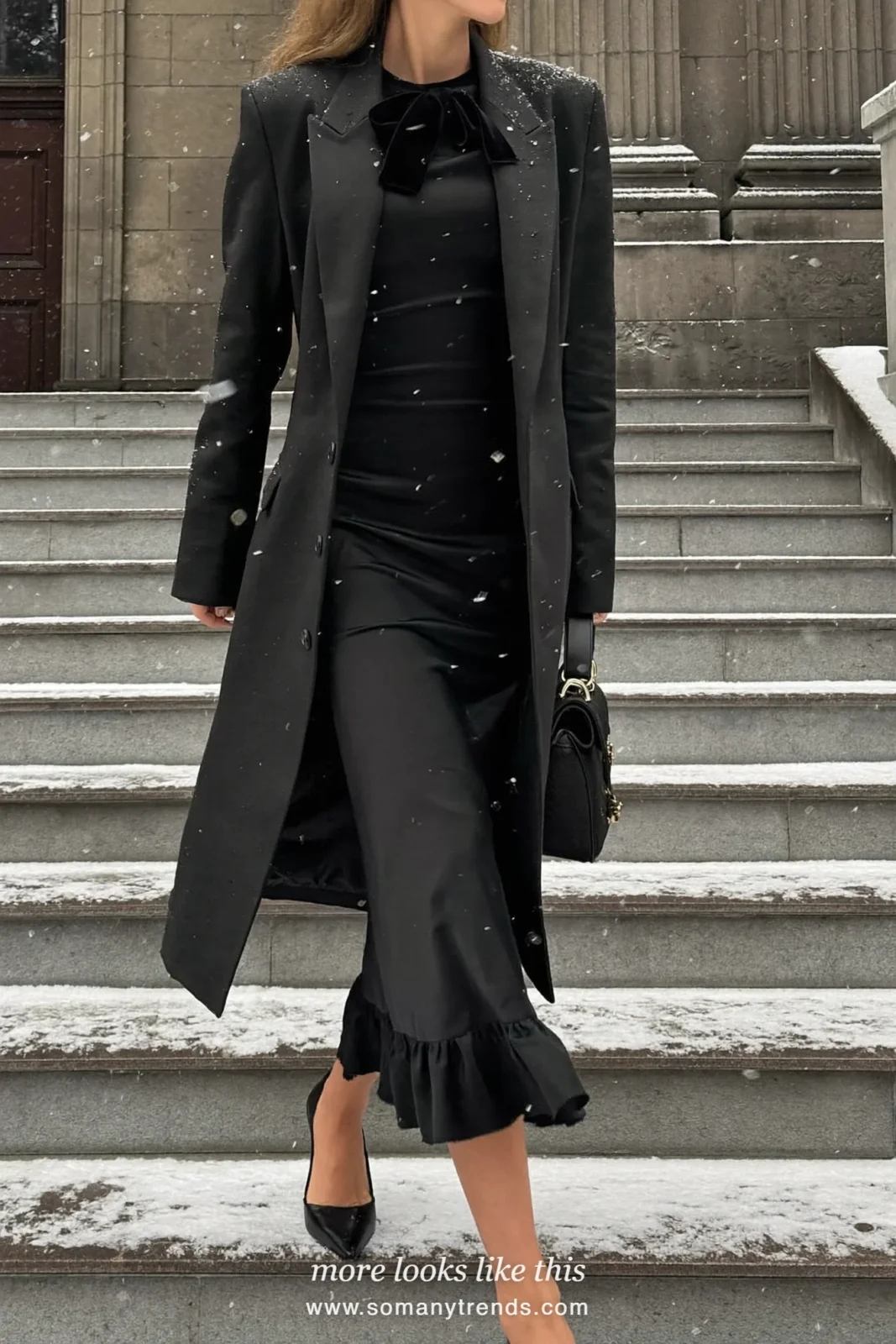 Woman in a black satin ruffle-hem midi dress with a velvet bow at the neck and black pumps outside a stone church, outfit 27