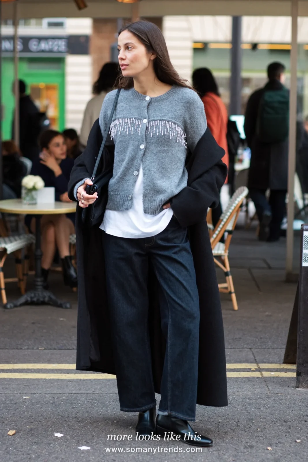 Woman in embellished beaded gray cardigan, white tee, dark wide-leg jeans and black boots, look 14
