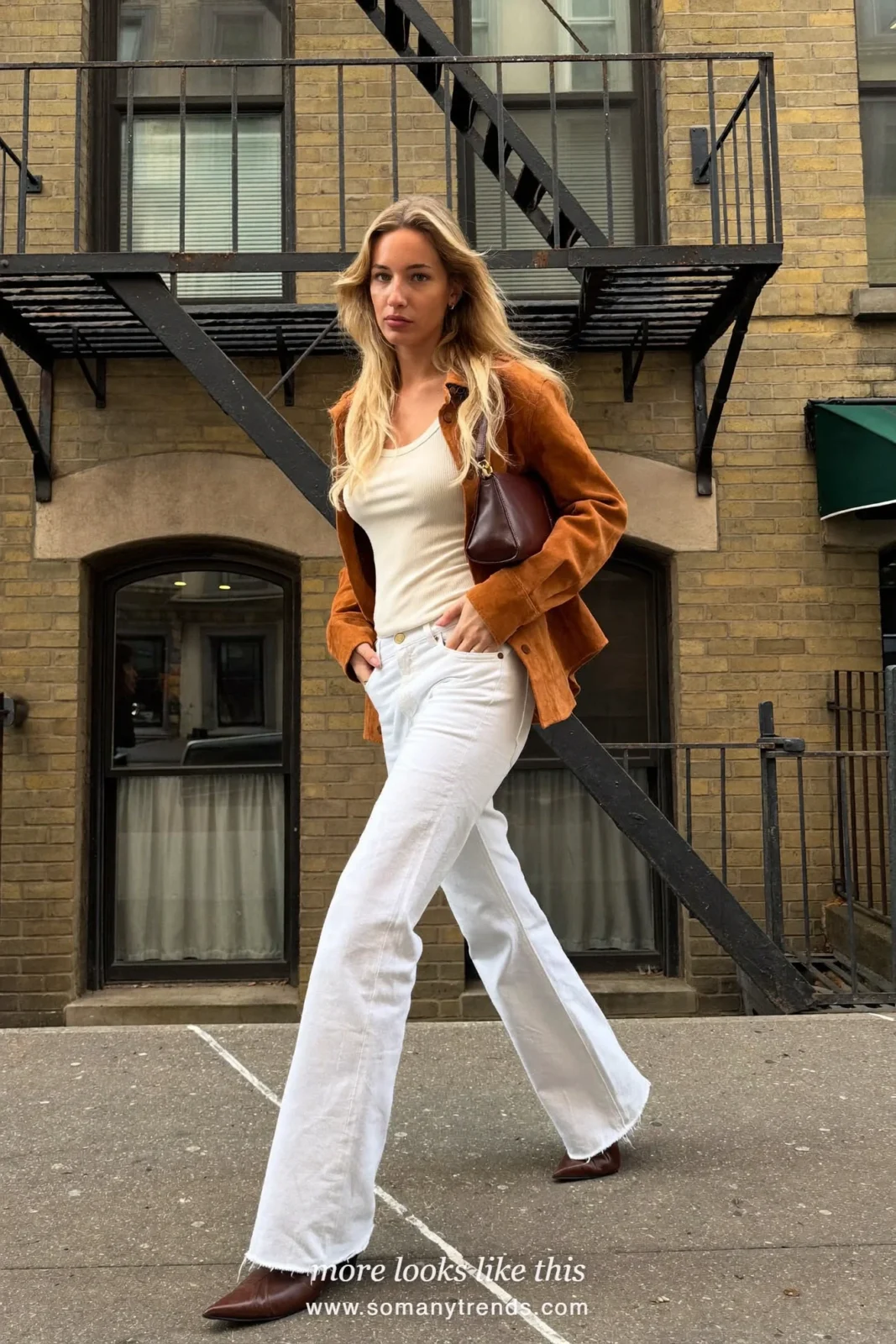 Woman in a rust suede shirt, white flare jeans and chocolate brown pointed boots on a New York street, outfit 3