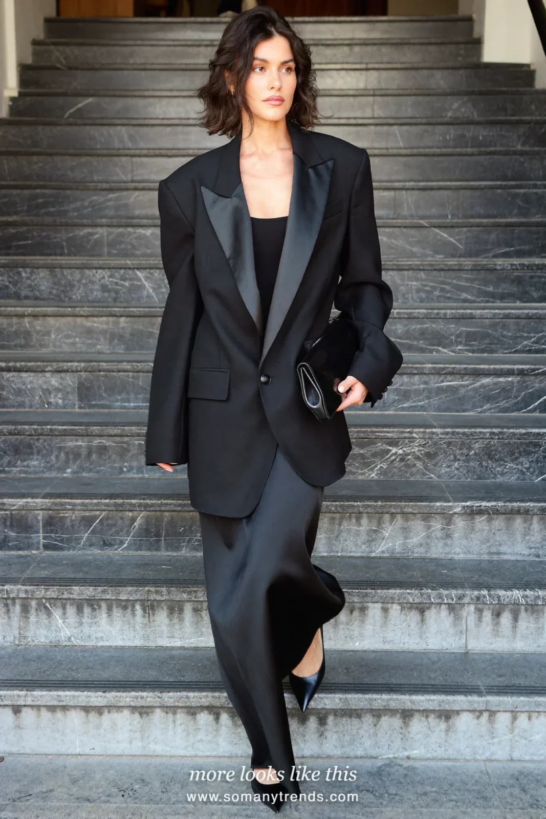 Woman in a black tuxedo jacket with a long black satin skirt on a staircase, outfit 17