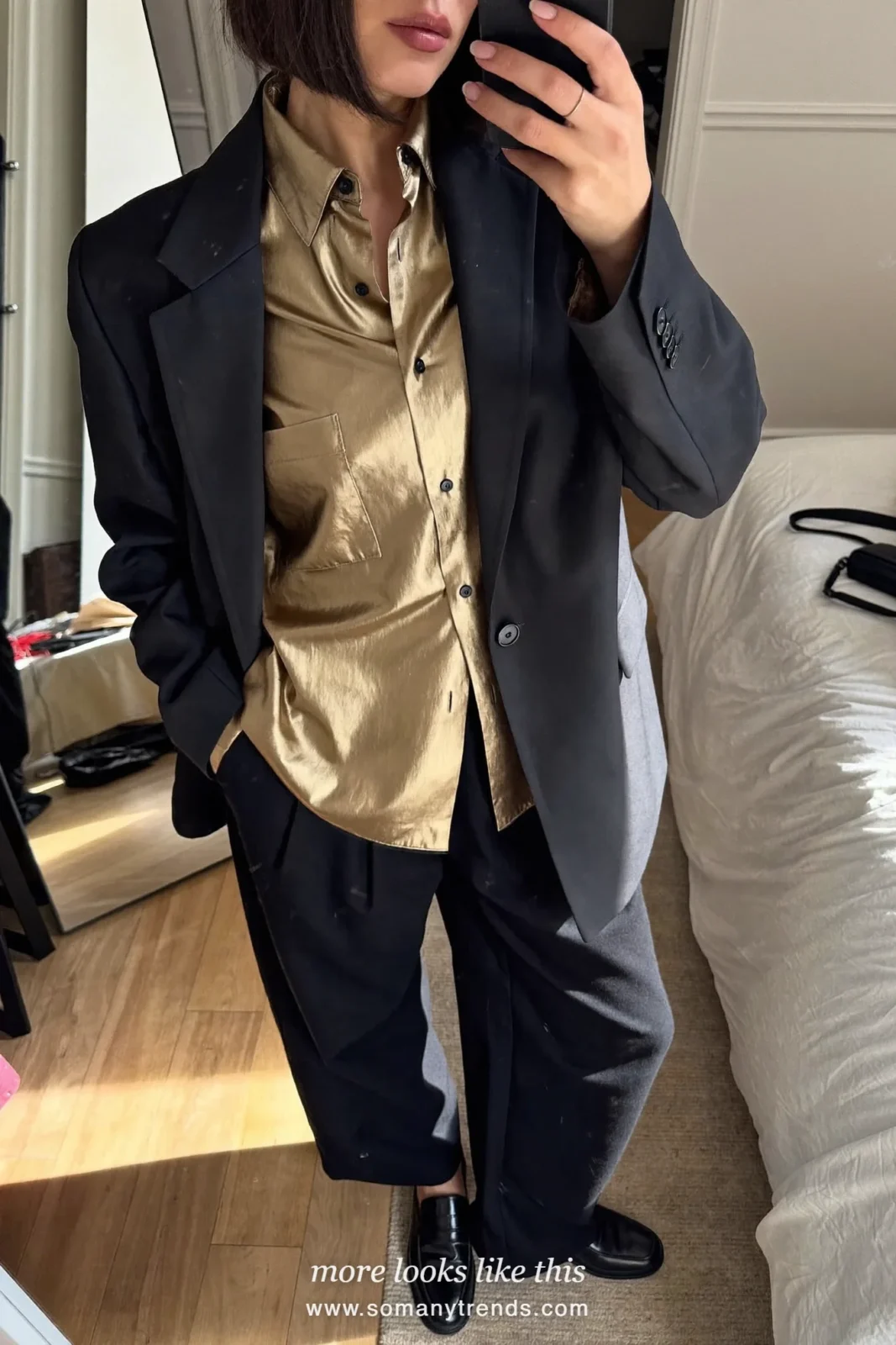 Woman in a gold metallic shirt, black oversize blazer, wide black pants and black loafers on a staircase, outfit 8