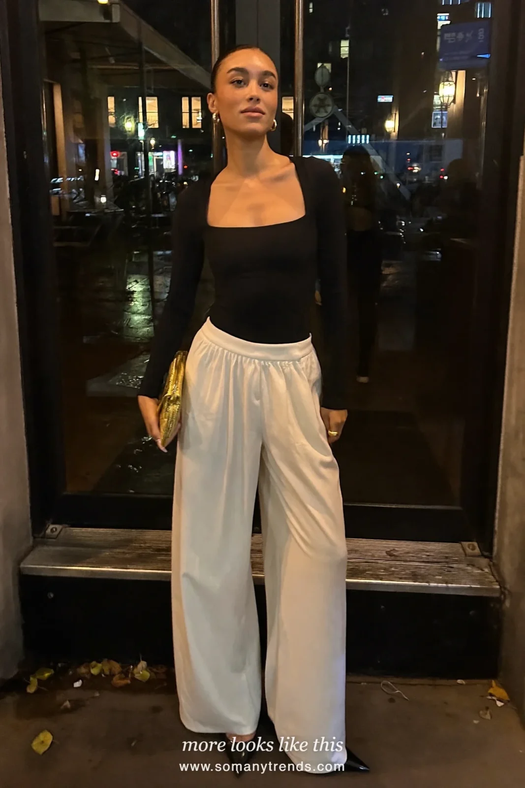 Woman in black scoop-neck top, ivory wide-leg pants, black pumps and metallic clutch, outfit 9