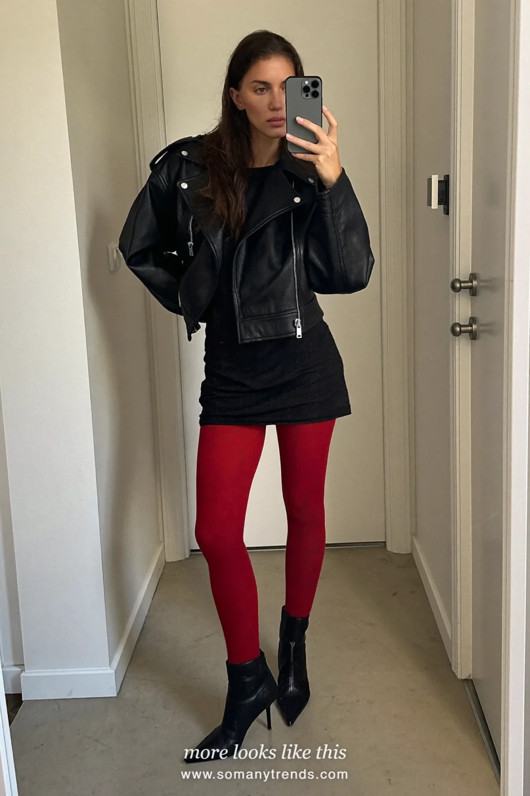 Woman in an oversized black leather jacket, black mini dress, sheer red tights and black pointed ankle boots, outfit 12