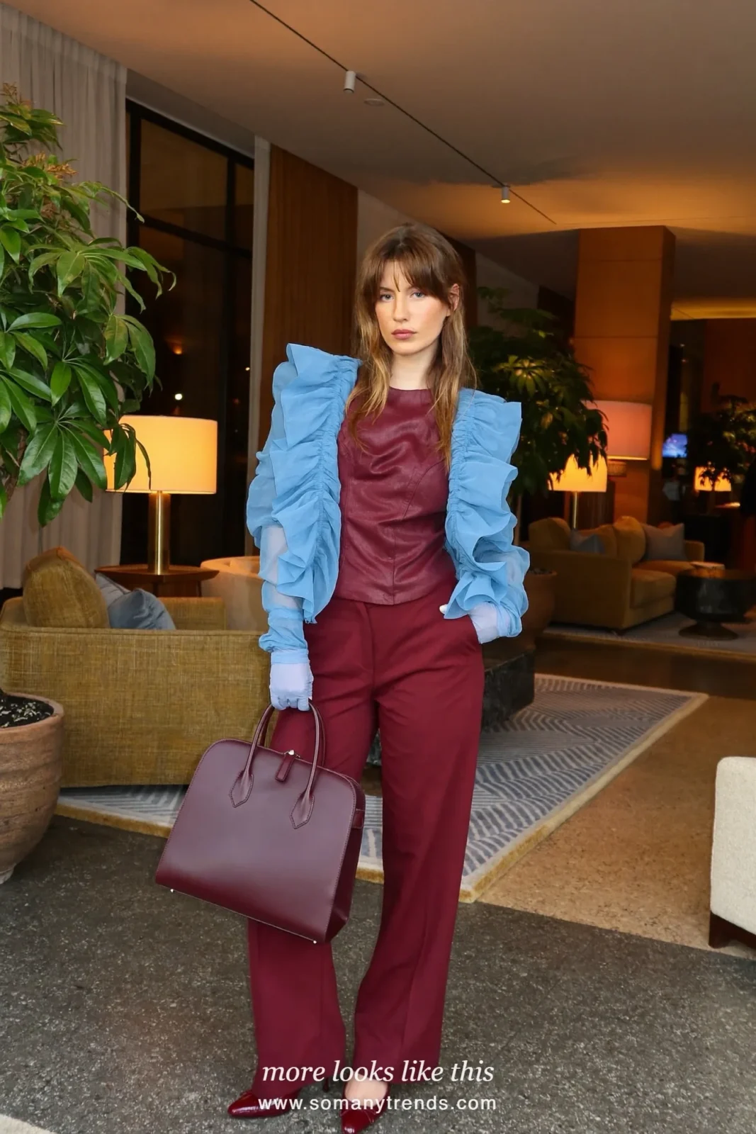 Woman in a baby blue organza ruffle jacket, baby blue gloves, burgundy wide-leg pants and a burgundy top-handle bag, outfit 4