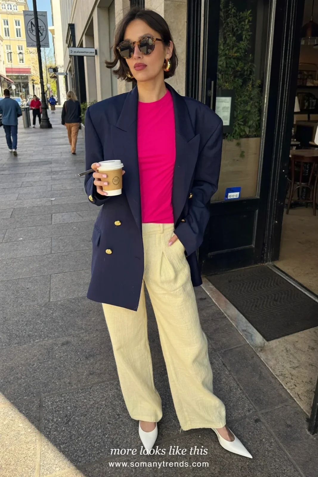 Woman in a navy blue blazer with gold buttons over a hot pink top, cream wide-leg pants and white slingbacks, outfit 1