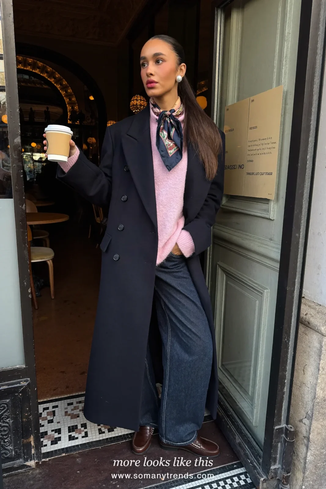 Woman in a navy blue double-breasted pea coat, baby pink crewneck sweater, dark jeans and brown loafers, outfit 11