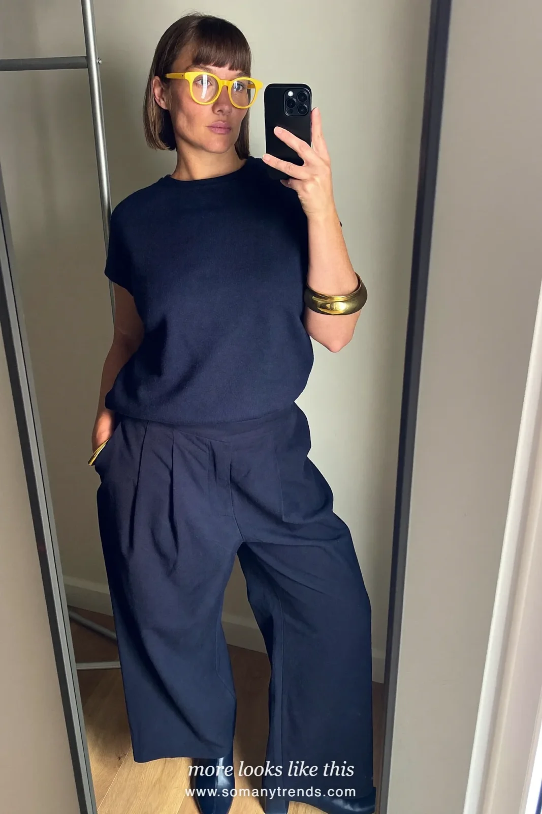 Woman in a blush pink wool coat over a navy blue turtleneck, navy trousers and navy ankle boots, outfit 12