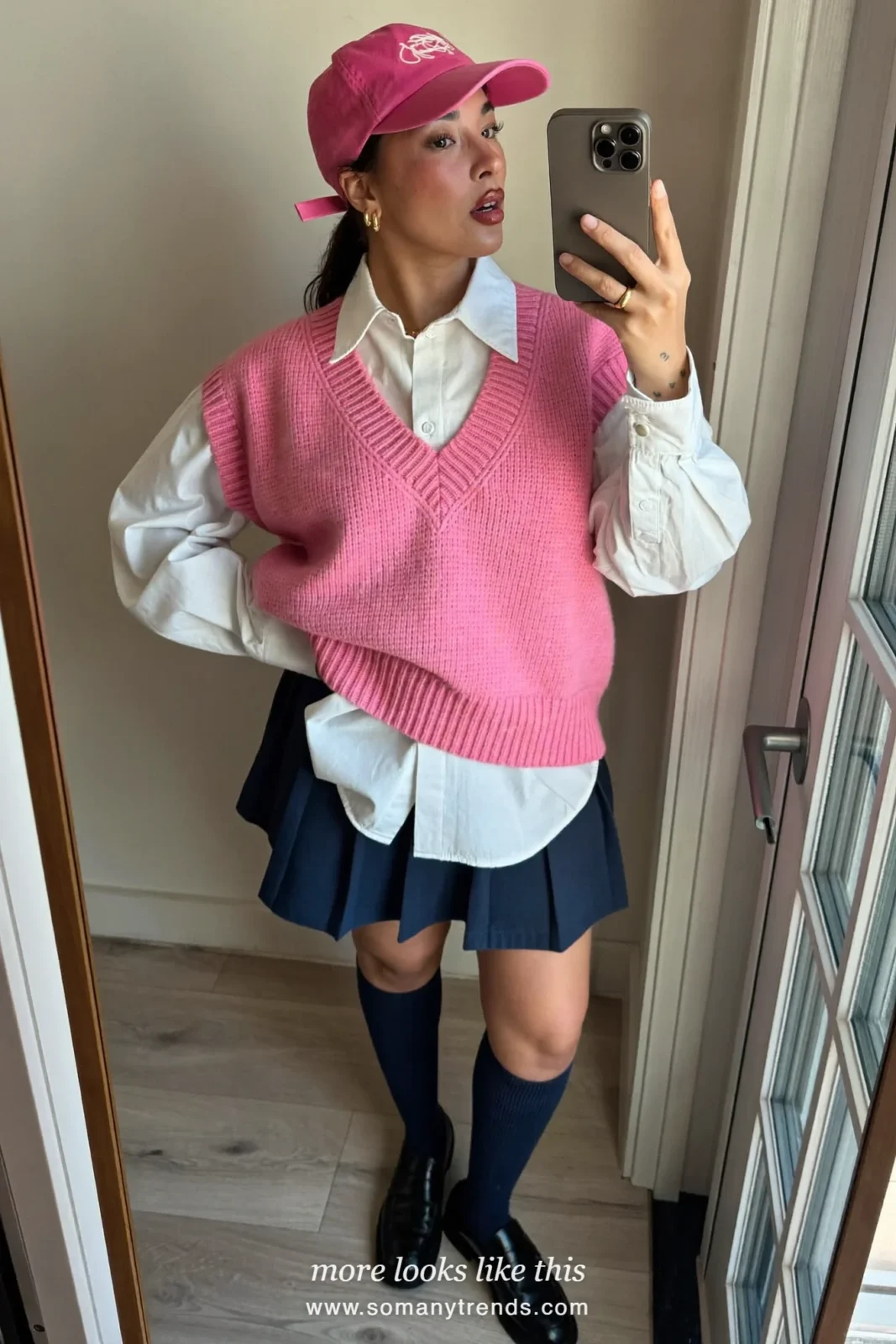 Woman in a navy blue pleated mini skirt, pink knit vest over a white shirt, navy socks and loafers, outfit 21