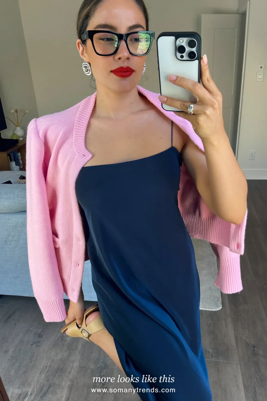 Woman in a navy blue slip midi dress with a baby pink cardigan over her shoulders and flat sandals, outfit 6