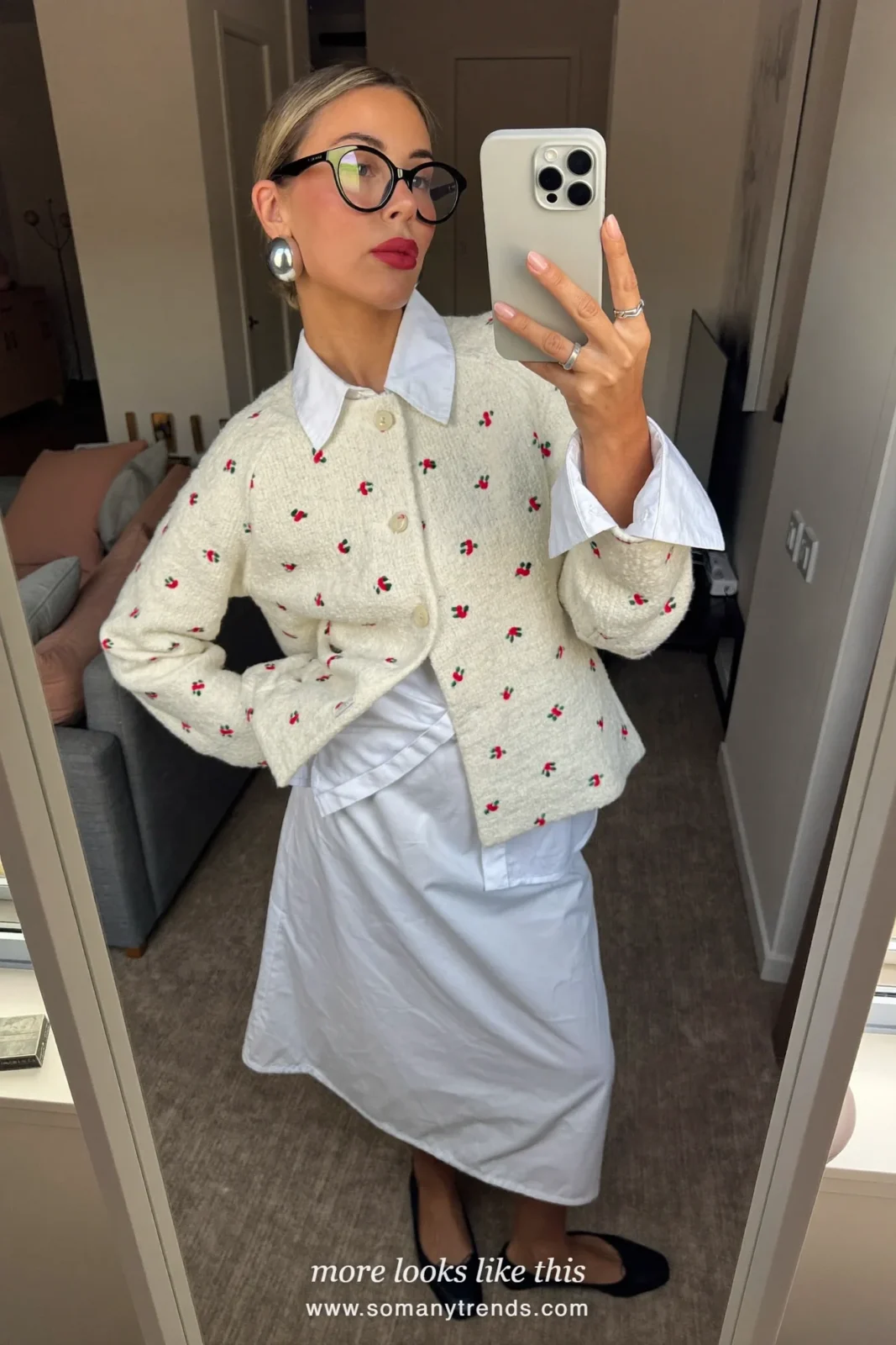 Cream cardigan with tiny red flowers over a white shirt with a white drop-waist midi skirt and black ballet flats, mirror selfie in a living room, outfit 6