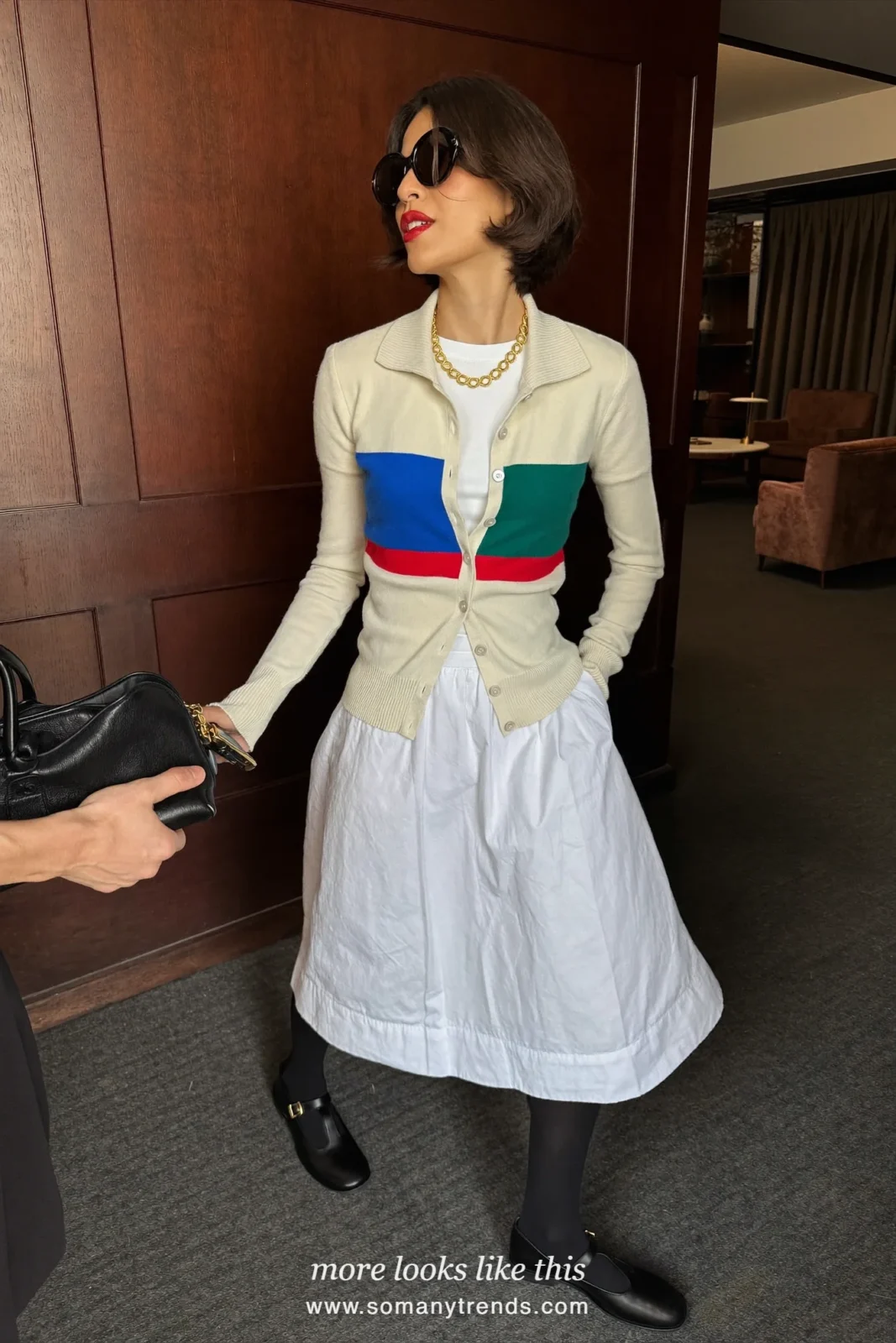 Cardigan with blue green and red chest band and cream collar with a full white midi skirt and black Mary Janes, outfit 10