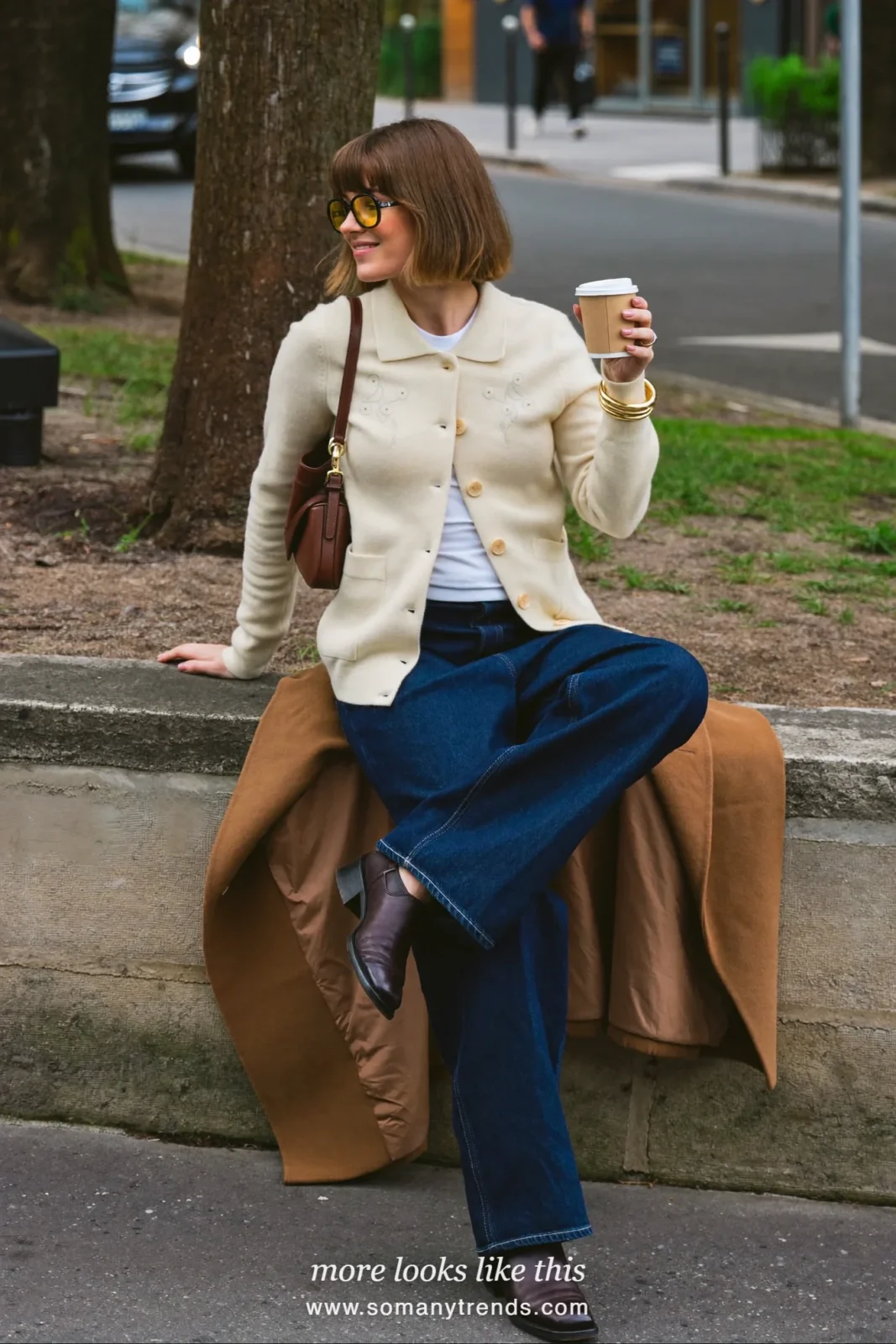 Long camel coat over a cream floral cardigan with dark straight jeans and brown leather boots, outfit 12