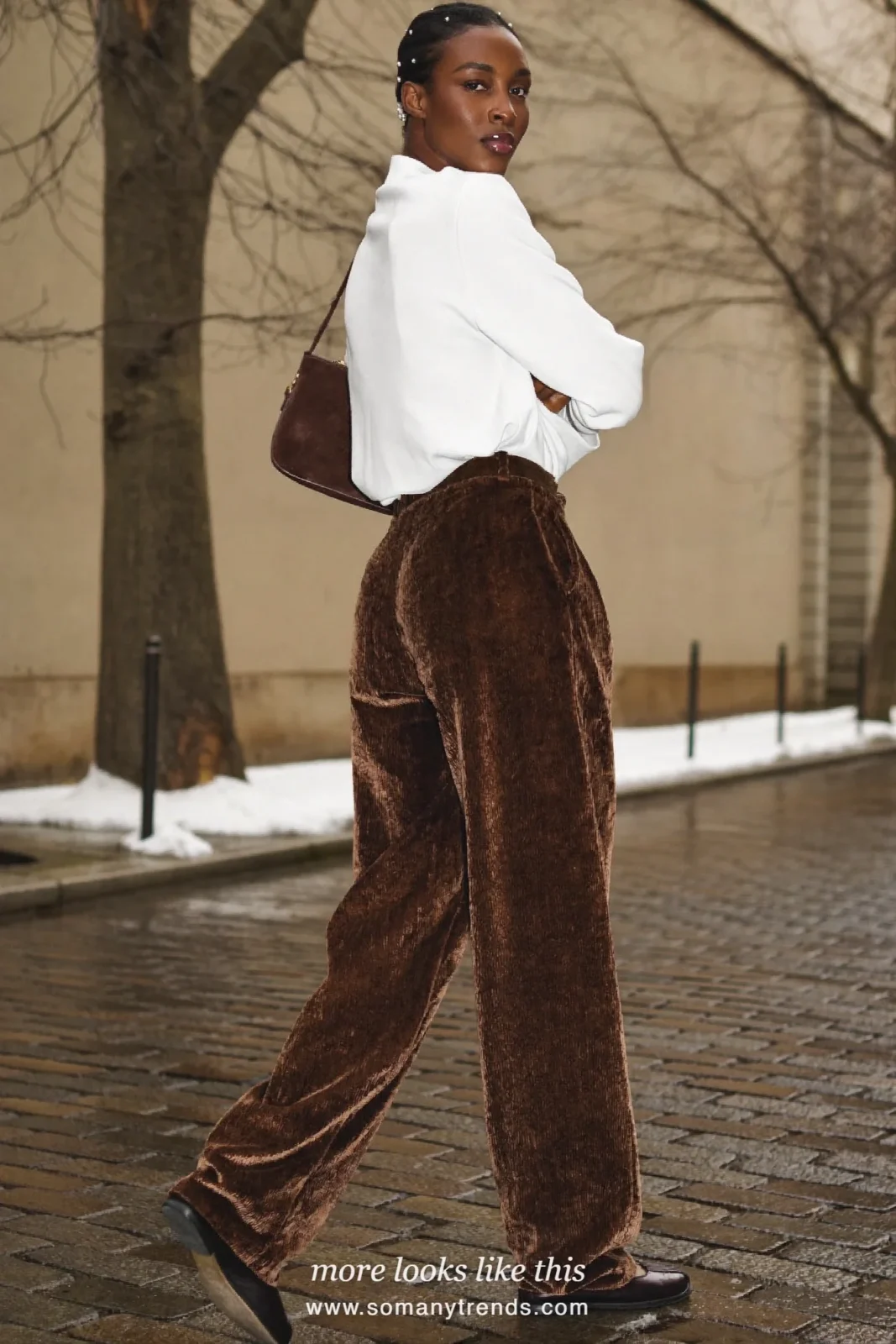 Woman in dark chocolate brown velvet wide pleated pants, white long-sleeve top, black flats and brown shoulder bag, outfit 2